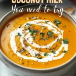 A steaming bowl of pumpkin soup coconut milk garnished with seeds and herbs.