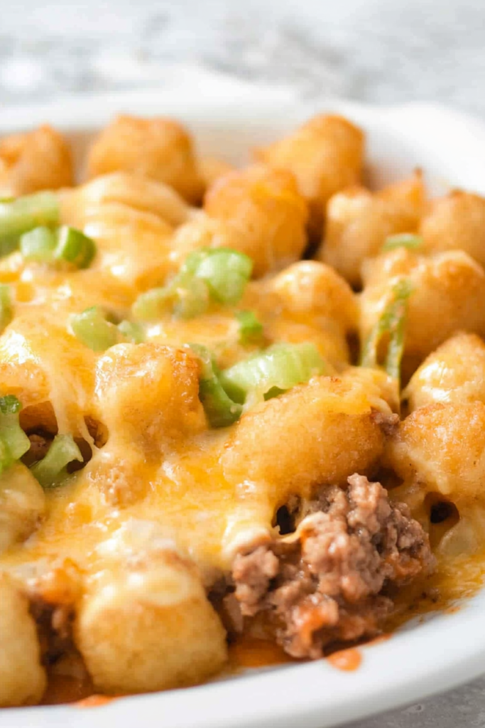Close-up of golden tater tots baked with melted cheese and beef.
