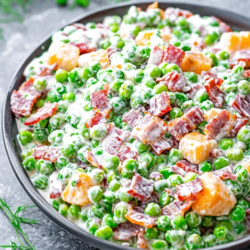 Classic Creamy Pea Salad topped with bacon crumbles and cheese, ready to serve.