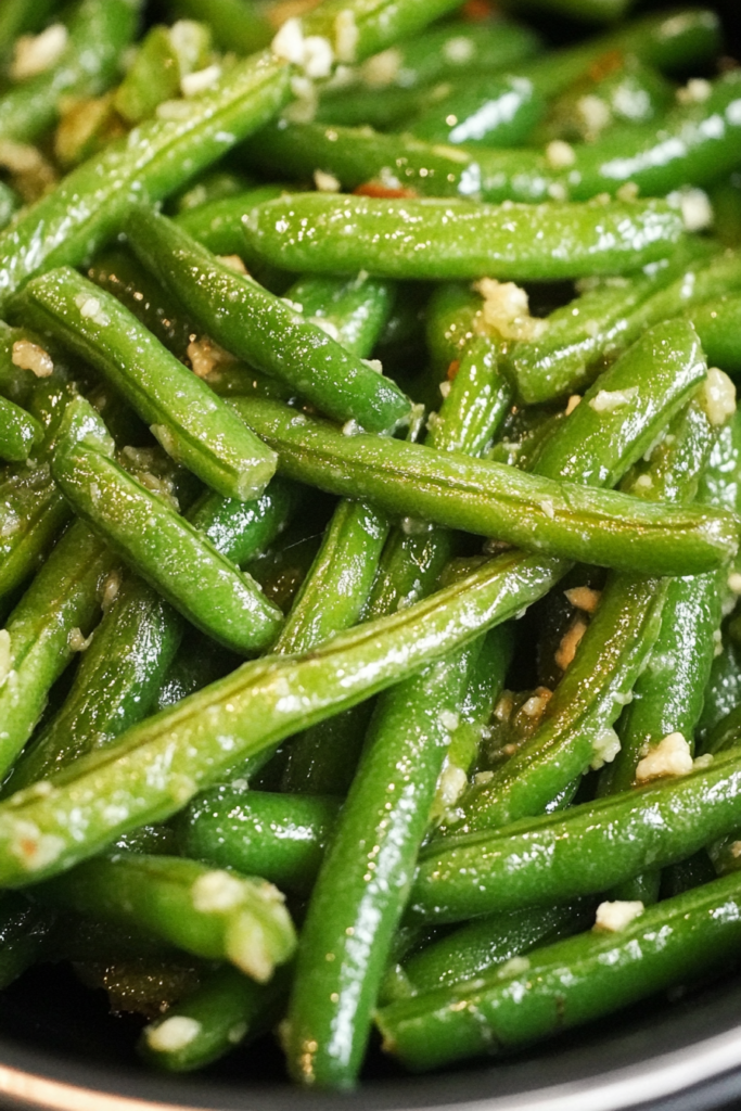 Close-up of glossy sautรฉed green beans served in a ceramic bowl.