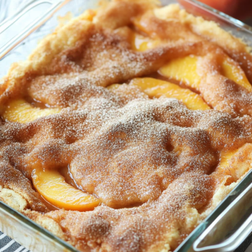 Whole pie in a glass dish with a golden crust and cinnamon-sugar dusting.