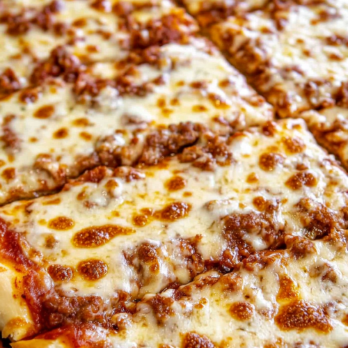 Close-up of a slice lifted from the pan, showing gooey cheese stretching from the crust.