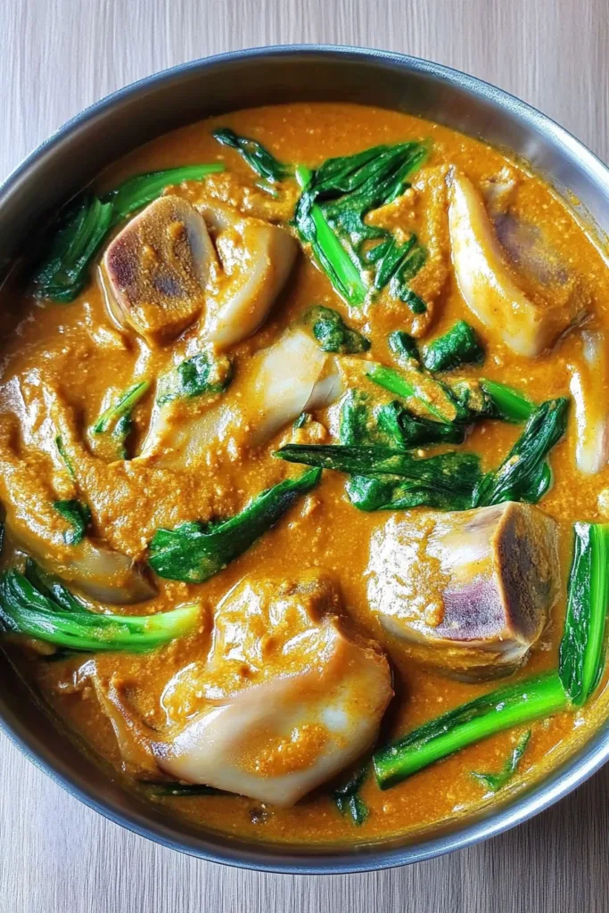 Serving bowl filled with creamy Filipino stew and fresh greens.