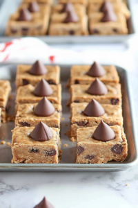 Freshly baked cookie bars sliced into squares and topped with chocolate.