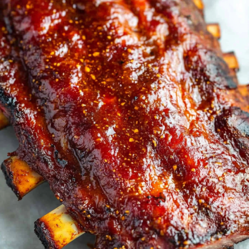 Juicy pork ribs resting on a plate, brushed with rich barbecue sauce.