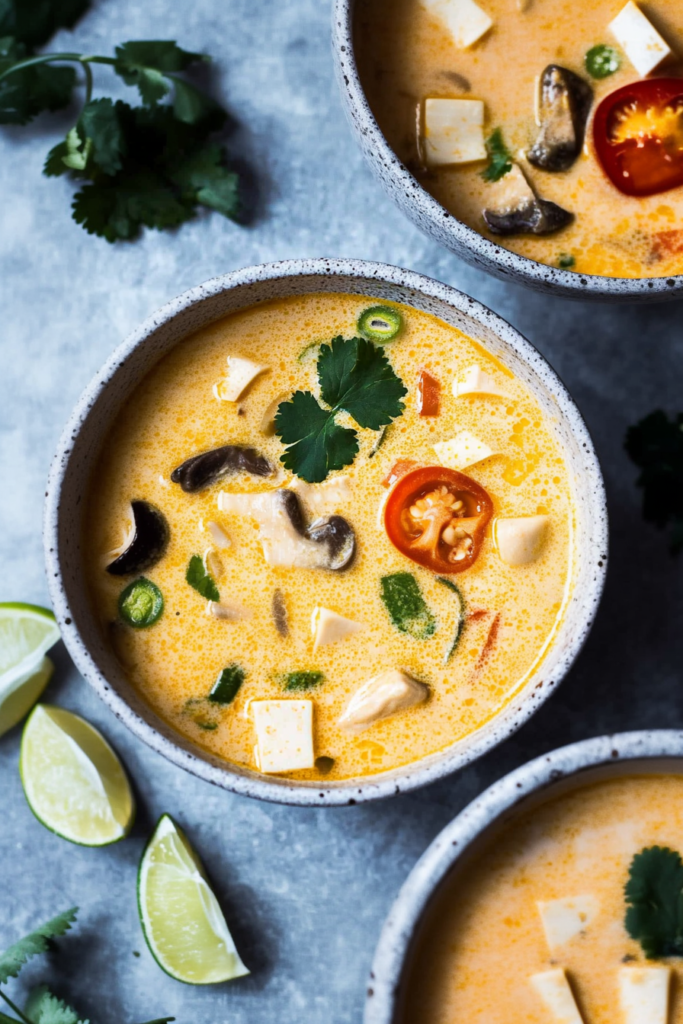 Bowl of dairy-free coconut soup topped with cilantro, tofu cubes, and Asian mushrooms.
