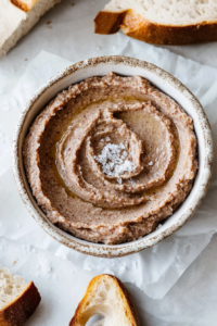 Creamy liver pรขtรฉ served in a small bowl with flaky salt and crusty bread.