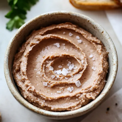 Bowl of silky pâté styled with fresh herbs and toasted bread on the side.