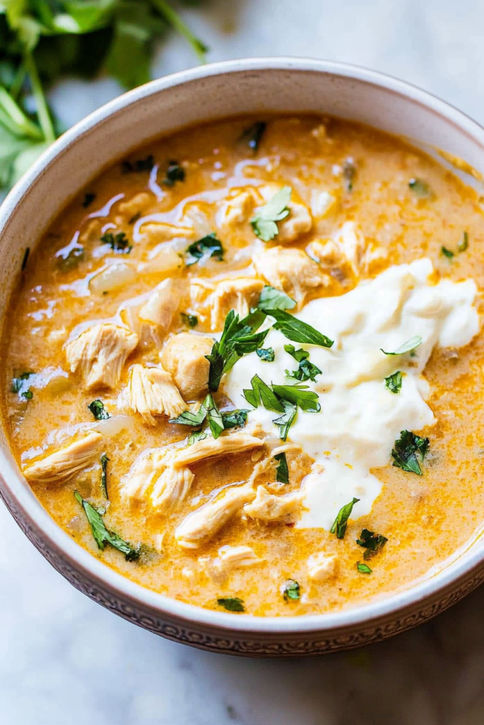 Close-up of a rich, creamy chicken stew with tender shredded chicken and herbs.