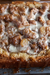 Slice of homemade apple cake with cinnamon sugar swirls, dusted with powdered sugar on a plate