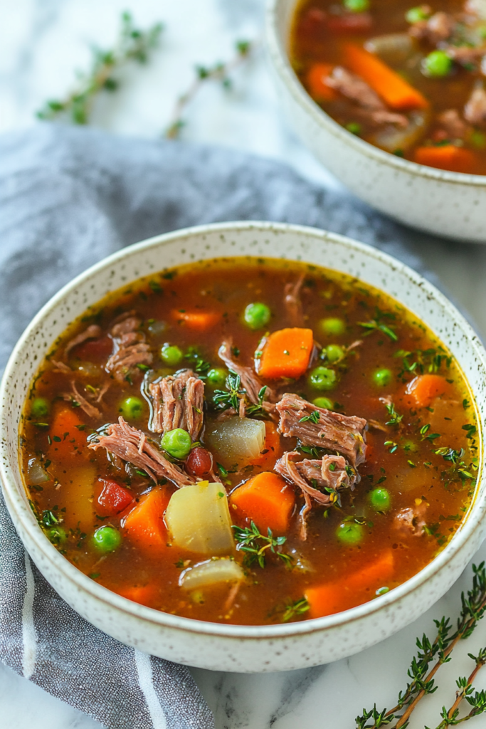 Comforting homemade soup with beef pieces, mixed vegetables, and savory broth served in a ceramic bowl.