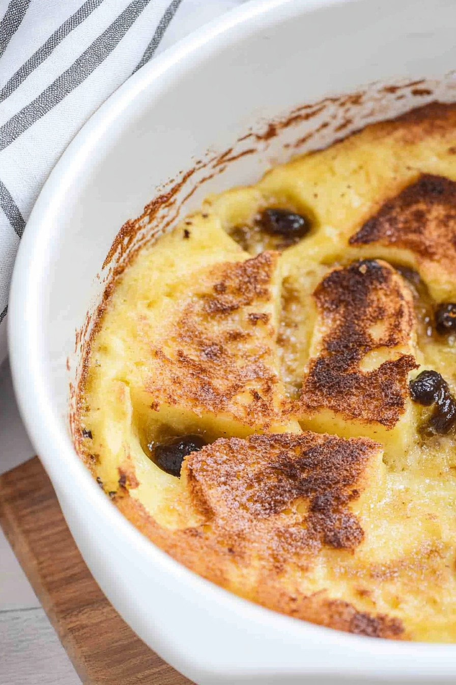 Comforting baked pudding with a caramelized crust and soft interior, served in a ceramic dish.