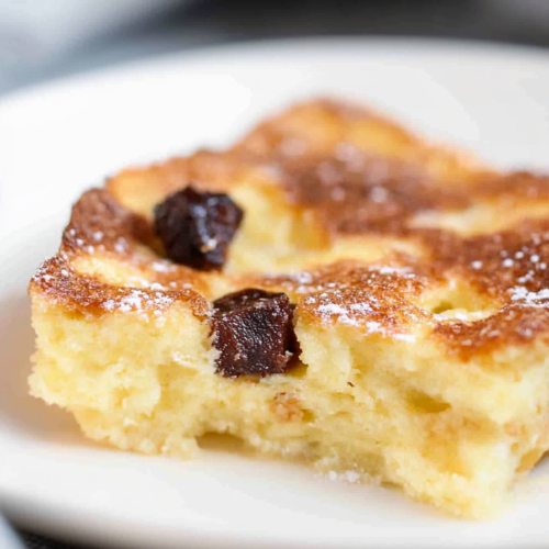 Final plated shot of Bread and Butter Pudding, finished with powdered sugar and cinnamon garnish.