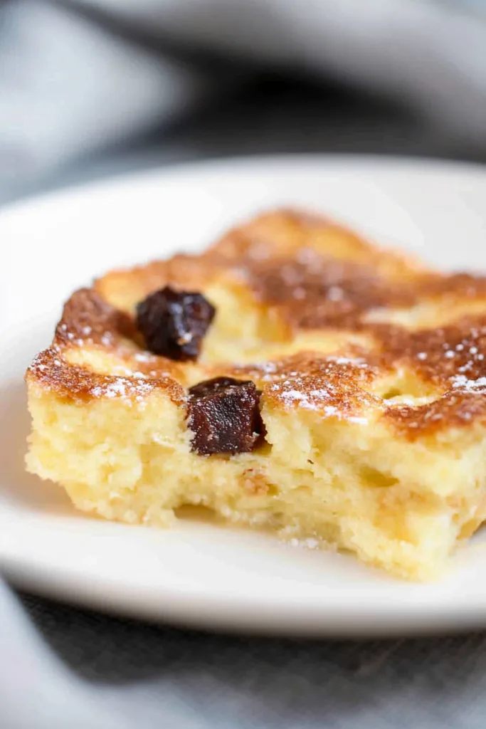 Final plated shot of Bread and Butter Pudding, finished with powdered sugar and cinnamon garnish.