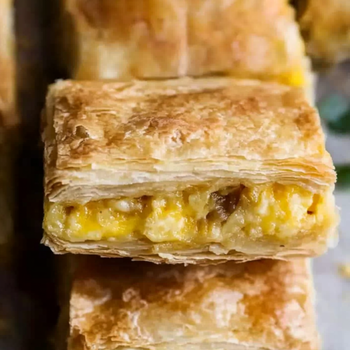 Close-up of flaky breakfast pastry showing the cheesy egg filling inside.