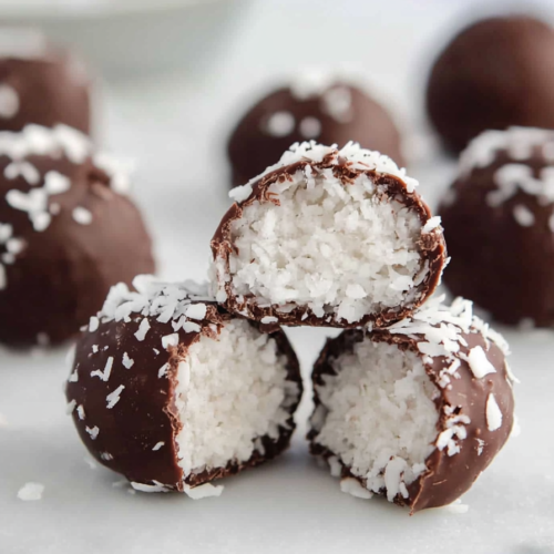 Chocolate-covered coconut bites with a soft white center, stacked and ready to serve.