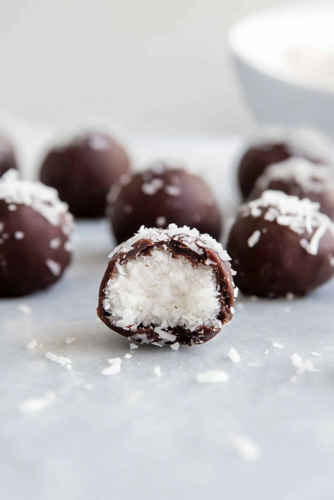No-bake coconut confections coated in chocolate, shown with a cut-open center.