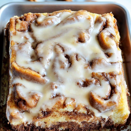Close-up of a tender cake with cinnamon filling and icing drizzled over the top.
