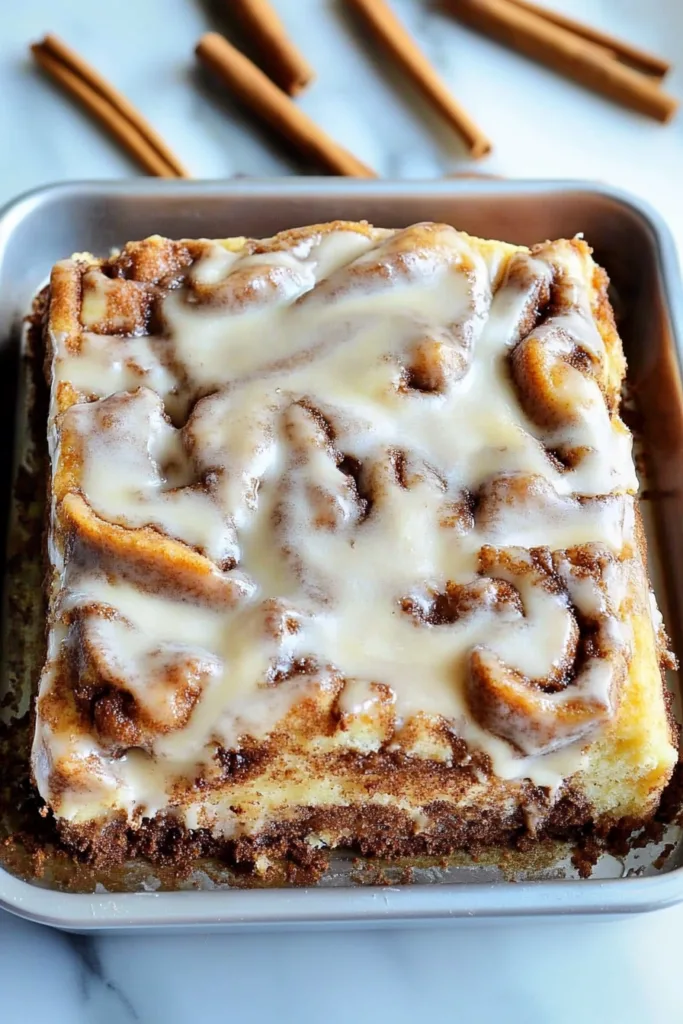 Close-up of a tender cake with cinnamon filling and icing drizzled over the top.