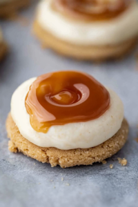 Single cookie on parchment paper, with smooth frosting and shiny caramel accent.