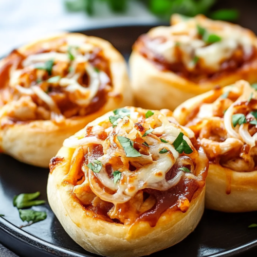 Close-up of cheesy rolled dough with barbecue-style chicken filling and herbs.
