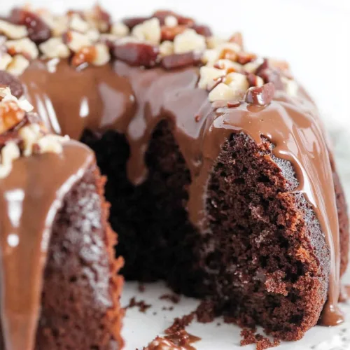 Slice of rich chocolate bundt cake showing moist interior and shiny frosting
