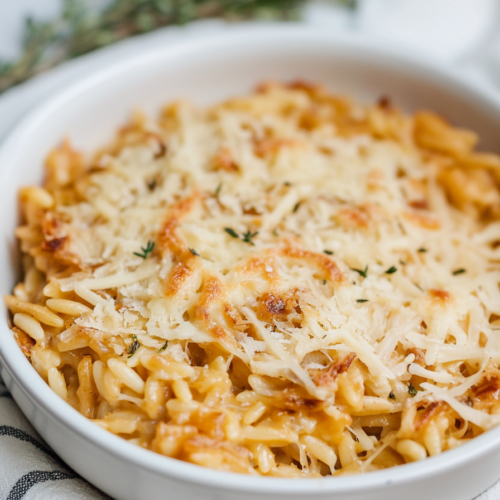 Warm, caramelized onion and cheese pasta bake served in a round baking dish.
