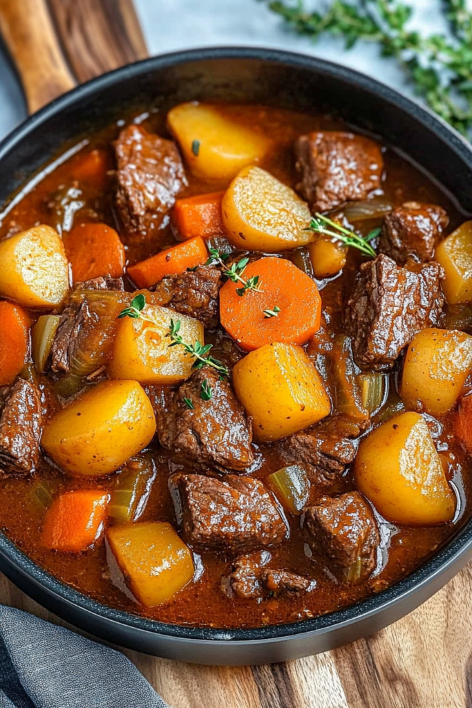 Rustic one-pot meal with beef cubes, carrots, onions, and thyme in broth.