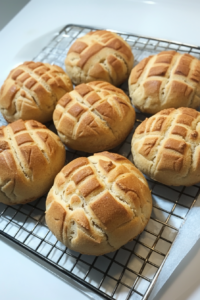 Soft sweet buns with a lightly cracked topping, cooling after baking