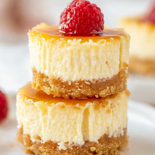 A plate of creamy bite-sized cheesecakes topped with glossy strawberries.