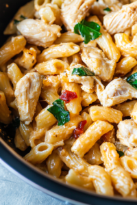 Hearty pasta dish featuring tender chicken chunks and sun-dried tomatoes against a creamy backdrop.