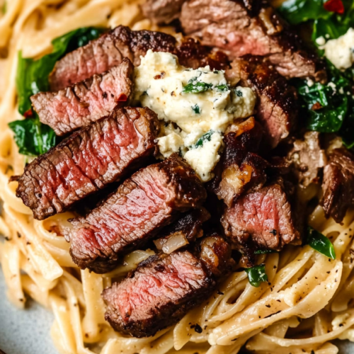Close-up of tender steak strips on top of rich, cheesy noodles.
