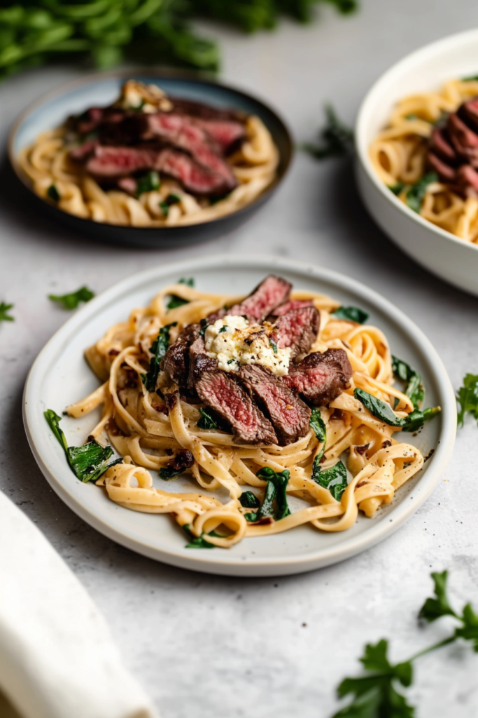Steak slices layered over saucy pasta with a creamy cheese topping.