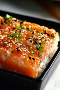 Baked sushi rice topped with spicy mayo, sesame seeds, and chopped green onions.