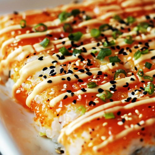 Warm sushi-style casserole with crisp edges and a colorful sauce drizzle.