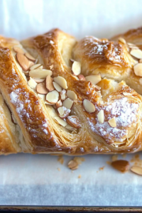 Close-up of flaky puff pastry with toasted almonds and powdered sugar.