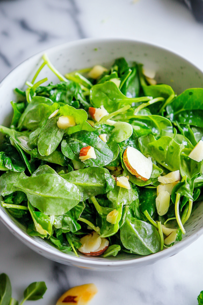 Close-up of a vibrant green salad made with tender greens and crunchy almond slices