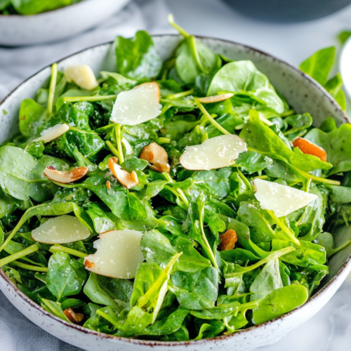 Healthy green salad served in a ceramic bowl, highlighting fresh leaves and nutty toppings