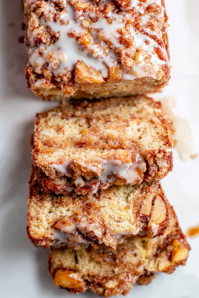 Sliced cinnamon swirl bread with baked apple pieces and sugary topping.