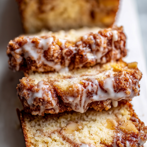 Thick slices of apple-studded quick bread with cinnamon swirl and sweet glaze.
