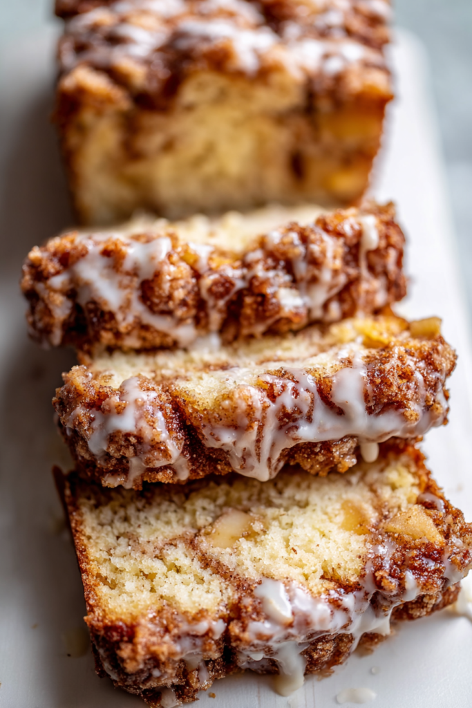 Thick slices of apple-studded quick bread with cinnamon swirl and sweet glaze.