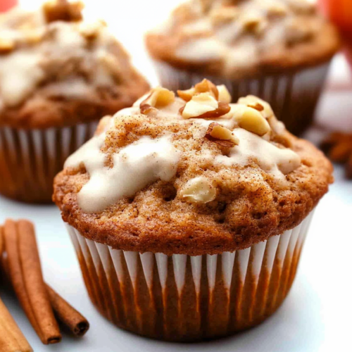 Warm, fluffy muffins with visible cinnamon specks and crunchy walnut topping.