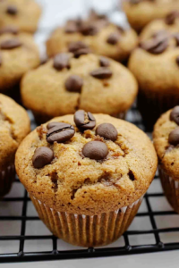 Close-up of golden-brown muffins with a moist texture and scattered chocolate pieces on top.