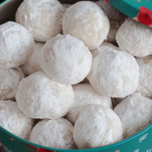 Buttery snowball cookies dusted generously in confectionersโ sugar and arranged for serving.