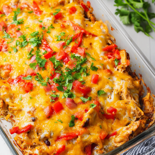 Cheesy baked chicken dish with roasted peppers served in a glass baking dish.