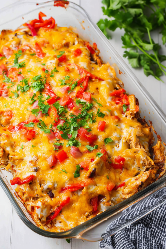 Cheesy baked chicken dish with roasted peppers served in a glass baking dish.