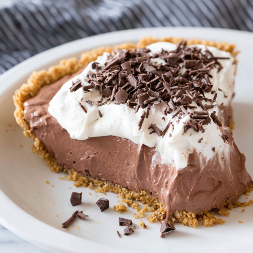 Slice of creamy chocolate pudding pie topped with whipped cream and dark chocolate shavings on a plate