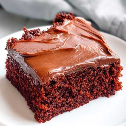 Close-up of rich, fudgy cake slices with thick chocolate icing and soft crumb texture.