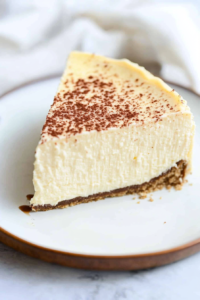 Close-up of a dense, velvety cheesecake slice with a golden cookie crust.
