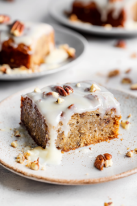 Golden-brown cake served with a shiny topping and sprinkled nuts, highlighting its indulgent crumb.